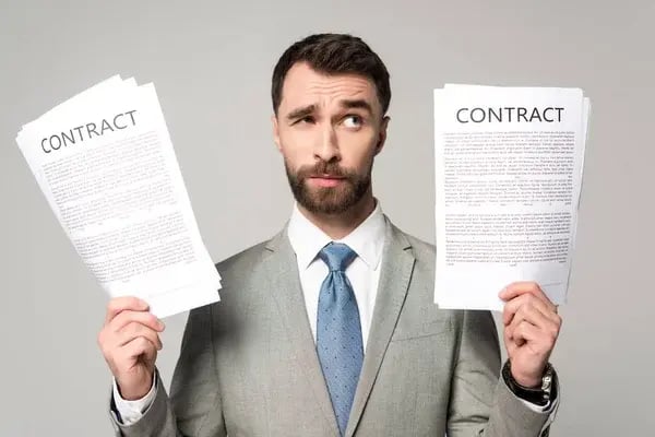 depositphotos_326972664-stock-photo-skeptical-businessman-holding-contracts-looking